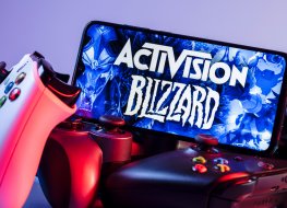 Smartphone with Activision Blizzard logo on the screen on top of game consoles