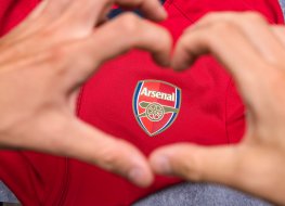 A flag with Arsenal logo and a person's hands in the shape of heart in from of its