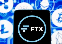 The FTX logo displays on a smartphone in front of crypto coin and token logos