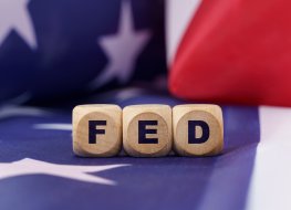 Back backdrop of the US flag with 3 wooden dice that have the inscription FED.