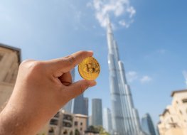 A hand holding bitcoin (BTC) coin in downtown Dubai.