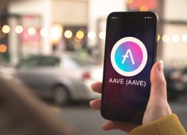 A person holding a smartphone with Aave logo on screen