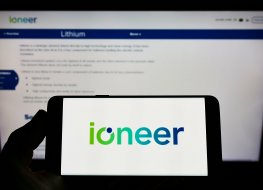 Person holding mobile phone with logo of Australian mining company company ioneer Ltd on screen in front of web page Focus on phone display