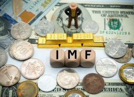International Monetary Fund (IMF) written on cubes on top of banknotes with gold bullion in the background