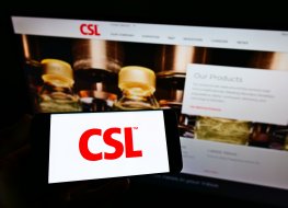 Person holding cellphone with logo of Australian pharmaceuticals company CSL Limited on screen in front of business webpage.