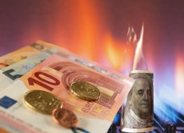 An image showing Euro banknotes lie next to a burning gas burner and a burning dollar, concept of energy crisis