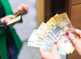 A woman in a green jacket is counting banknotes of Australian dollars.