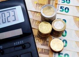 Energy and financial crisis in Europe in 2023. The ever-increasing cost of energy, food and goods. Calculator and a lot of euro coins on the background of banknotes of 50 euros