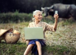  Elderly Vietnamese woman using a laptop and smartphone 