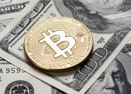 A bitcoin token rests on dollar notes 