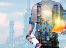 engineer in a protective helmet with a background of an oil refining plant