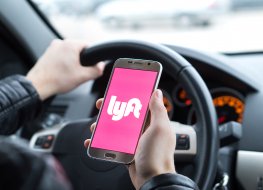 Lyft stock forecast: Will ride-hailing app recover from plunge? Lyft driver holding smartphone in car. Lyft is an American company offering transportation services online. Illustrative editorial.