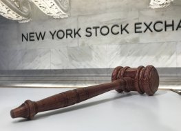 Gavel in front of NYSE logo on a wall