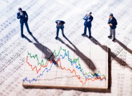 Businessmen and stock markets Mini-statues of businessmen observing stock market charts showing volatility