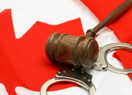 A gavel and handcuffs on a Canadian flag