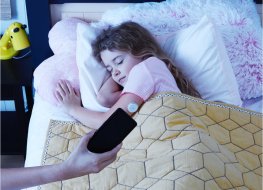 Biosensor A person lies in bed wearing a sensor to monitor her sleep