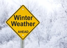 A winter weather sign with a snowy cold setting behind it
