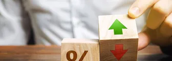 A businessman holds wooden blocks with percentages and up or down arrows. Mortgage and loan rates. Interest rate, shares, rating. The concept of business and finance.