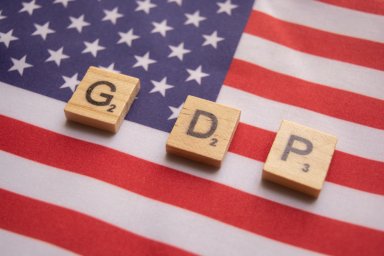 Finance Concept, GDP or Gross domestic product wooden block letters on US Dollar flag