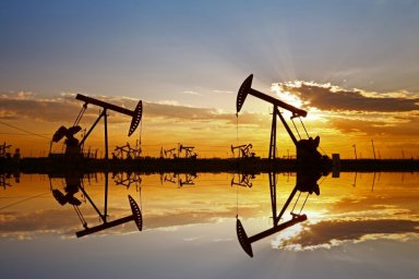 Oil wells pictured in an oil field, silhouetted against clouds