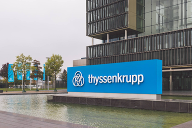 Thyssenkrupp logo displayed on a blue corporate sign outside a modern office building