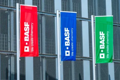 BASF-Unternehmensflaggen in Rot, Blau und Grün vor einem Industriegebäude
