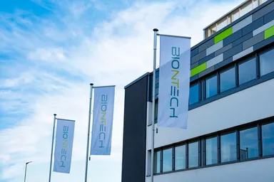 BioNTech-Flaggen vor einem modernen Bürogebäude