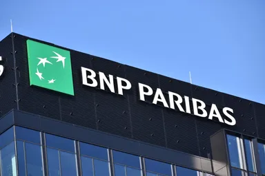 Logo BNP Paribas affiché sur la façade d'un immeuble de bureaux moderne sous un ciel bleu dégagé