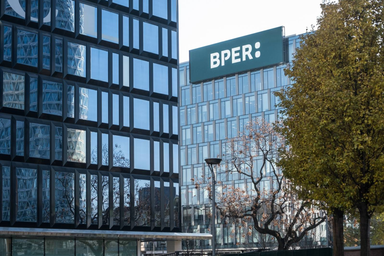 Logo BPER esposto sul tetto di un moderno edificio per uffici con facciate in vetro.