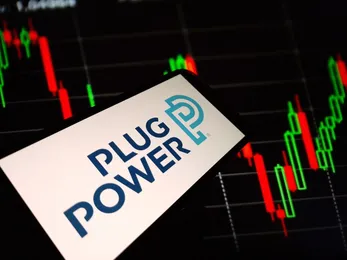 Plug Power logo displayed on a smartphone screen with a stock market candlestick chart in the background