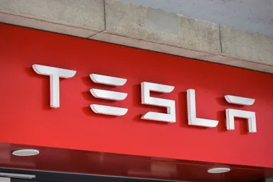 Tesla-Logo auf einem roten Ladenschild an einer Gebäudefassade