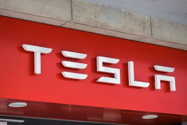 Tesla logo displayed on a red storefront sign mounted on a building exterior