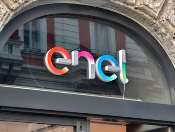 Logo Enel esposto sulla facciata in vetro di un edificio sotto un arco in pietra