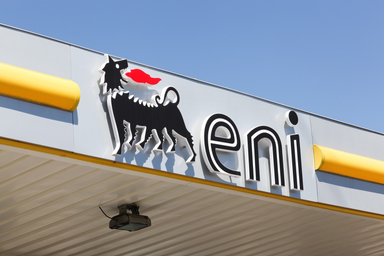 Eni logo with the six-legged dog symbol displayed on the exterior of a petrol station under a clear blue sky.
