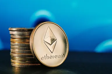 Ethereum cryptocurrency coin placed on a stack of coins with a blurred blue background