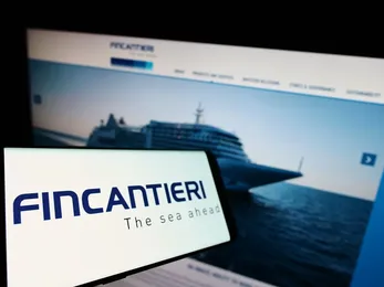 Smartphone che mostra il logo Fincantieri con un'immagine sfocata di una nave da crociera su un sito web sullo sfondo