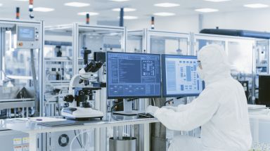 Over the shoulder view of a scientist in protective clothes in a laboratory