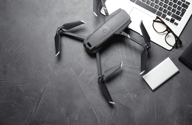 Consumer-style drone placed on a desk beside a laptop, representing the growing UAV and counter-drone technology market