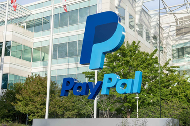 PayPal logo sign displayed outside a modern glass office building surrounded by green trees