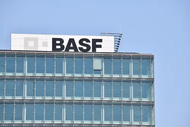 BASF logo displayed on top of a modern glass office building under a clear blue sky.