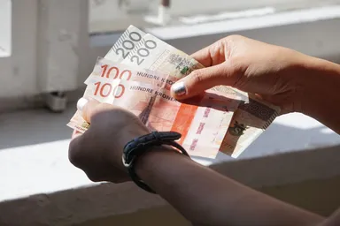 Hands counting Norwegian kroner and Polish zloty banknotes.