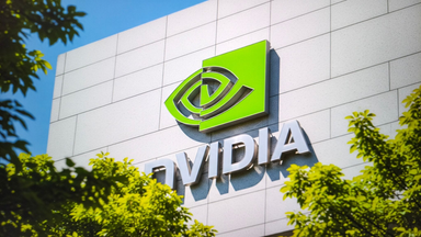 NVIDIA logo displayed on the exterior wall of a modern office building surrounded by green trees.
