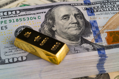 Lingotto d'oro posizionato su banconote da $100 dollari USA