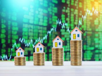 Model houses and coins on table representing finance