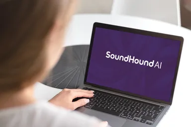 Person using a laptop displaying the SoundHound AI logo on the screen