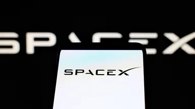 Logo SpaceX visualizzato sullo schermo di uno smartphone con sfondo nero e marchio sfocato sul retro