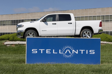 Logo Stellantis su insegna blu con pickup RAM bianco esposto sopra davanti a un edificio aziendale