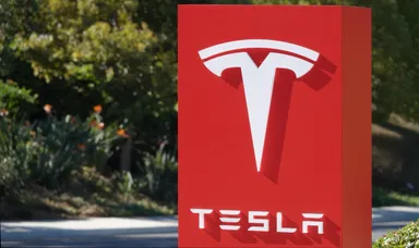 Tesla logo displayed on a red sign outdoors