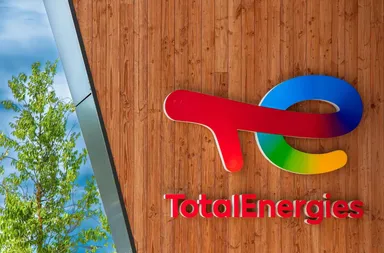 Logo TotalEnergies monté sur un mur en bois à l'extérieur d'un bâtiment