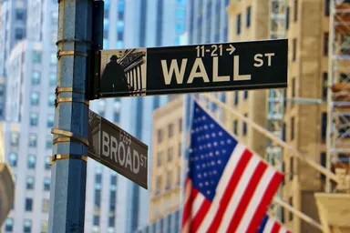 Znak Wall Street z amerykańską flagą i budynkami miasta w tle